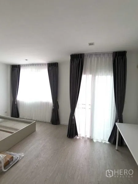 Home Office for rent or sale - Sunlit bedroom with floor-to-ceiling curtains and access to a small balcony.