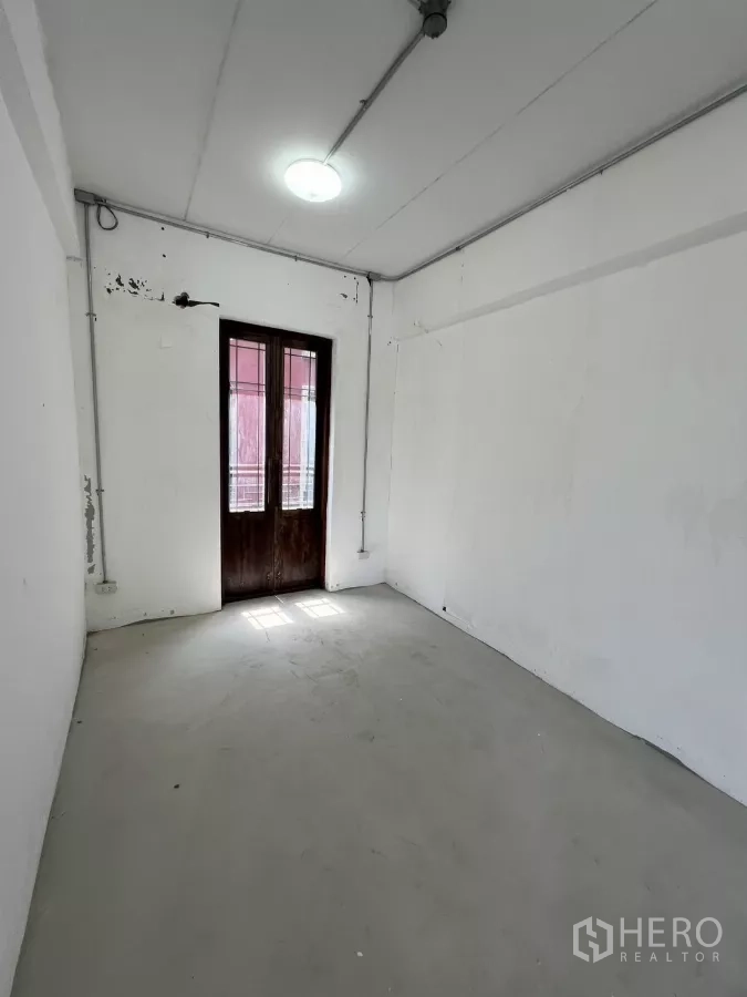 零售空间 出租在Khlong Toei, Bangkok - 狭长白色房间，木门采光良好。