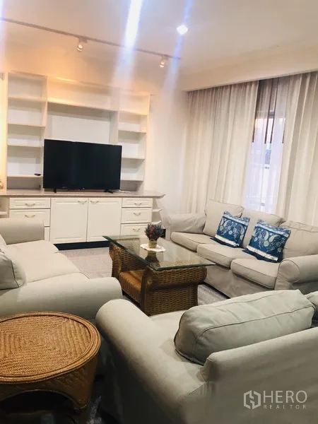 คอนโด ให้เช่าในWatthana, Bangkok - ห้องนั่งเล่นกว้าง โซฟาสีอ่อน ชั้นบิลท์อิน และโต๊ะกลางกระจก