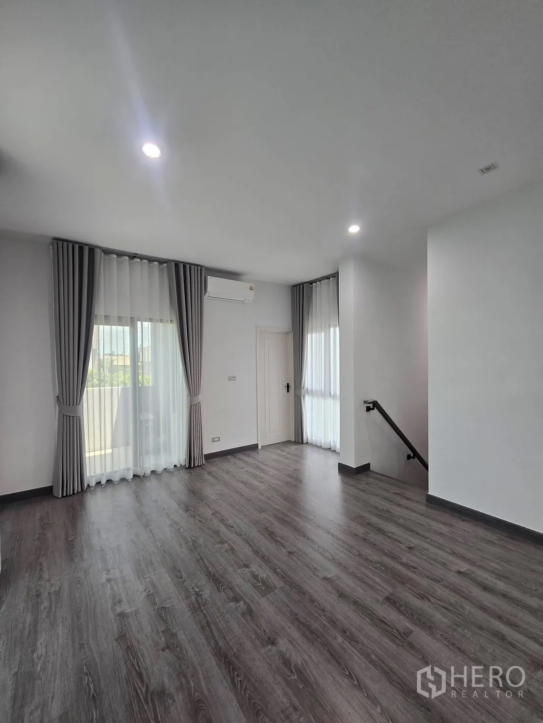 Semi-detached House for rent in Suan Luang, Bangkok - Spacious upper room with wood-style flooring, curtains and staircase access.