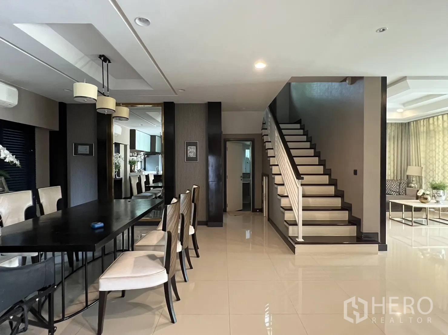 Detached House for rent or sale in Bang Kapi, Bangkok - Dining zone with a long black table and a staircase to the upper floor.