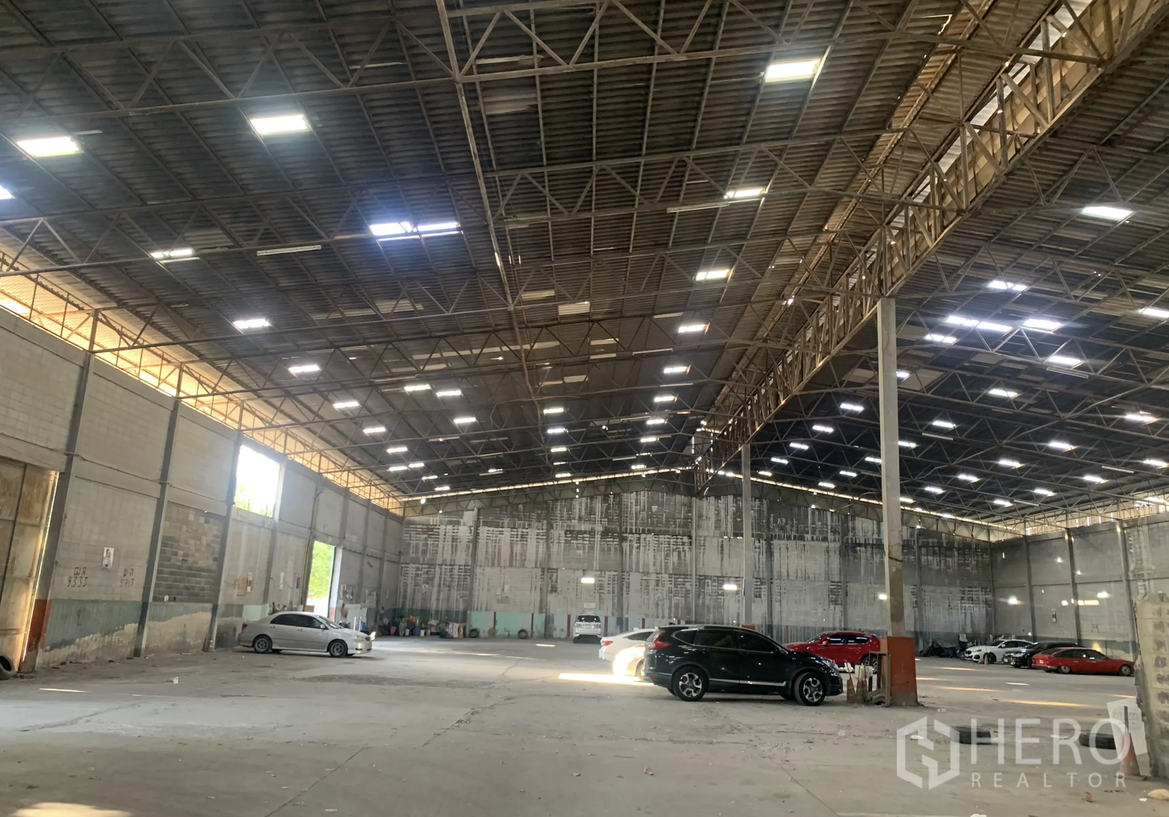 Warehouse for rent in Yan Nawa, Bangkok - Open warehouse bay with multiple large door openings, bright ceiling lights, and a wide concrete floor.