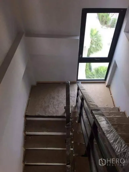Townhouse for sale in Yan Nawa, Bangkok - Staircase landing with protective railing wrap and a tall window bringing in natural light.