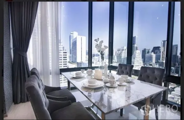 คอนโด ให้เช่าในBang Rak, Bangkok - มุมทานอาหารโต๊ะหินอ่อนริมห้องกระจกสูง จากพื้นจรดเพดาน มองเห็นวิวสกายไลน์กรุงเทพฯ ตอนกลางวัน