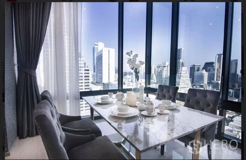 คอนโด ให้เช่าในBang Rak, Bangkok - มุมทานอาหารโต๊ะหินอ่อนริมห้องกระจกสูง จากพื้นจรดเพดาน มองเห็นวิวสกายไลน์กรุงเทพฯ ตอนกลางวัน