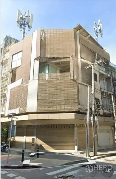 Shophouse for sale - Corner shophouse exterior with metal screen facade and roller shutters on a city street.