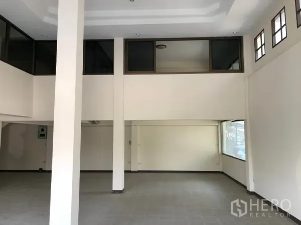 Shophouse for sale in Lam Luk Ka, Pathum Thani - Double-height ground floor showing an open-plan area with tiled floor and mezzanine windows.