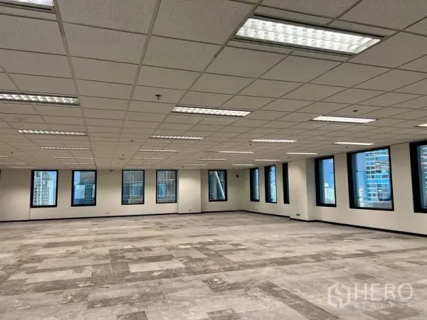 สำนักงาน ให้เช่าในKhlong Toei, Bangkok - ภายในสำนักงานขนาดใหญ่ พื้นปูกระเบื้องบางส่วน ไฟฟลูออเรสเซนต์แบบฝัง และหน้าต่างกรอบสีดำมองเห็นสกายไลน์