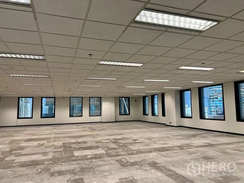 สำนักงาน ให้เช่าในKhlong Toei, Bangkok - ภายในสำนักงานขนาดใหญ่ พื้นปูกระเบื้องบางส่วน ไฟฟลูออเรสเซนต์แบบฝัง และหน้าต่างกรอบสีดำมองเห็นสกายไลน์