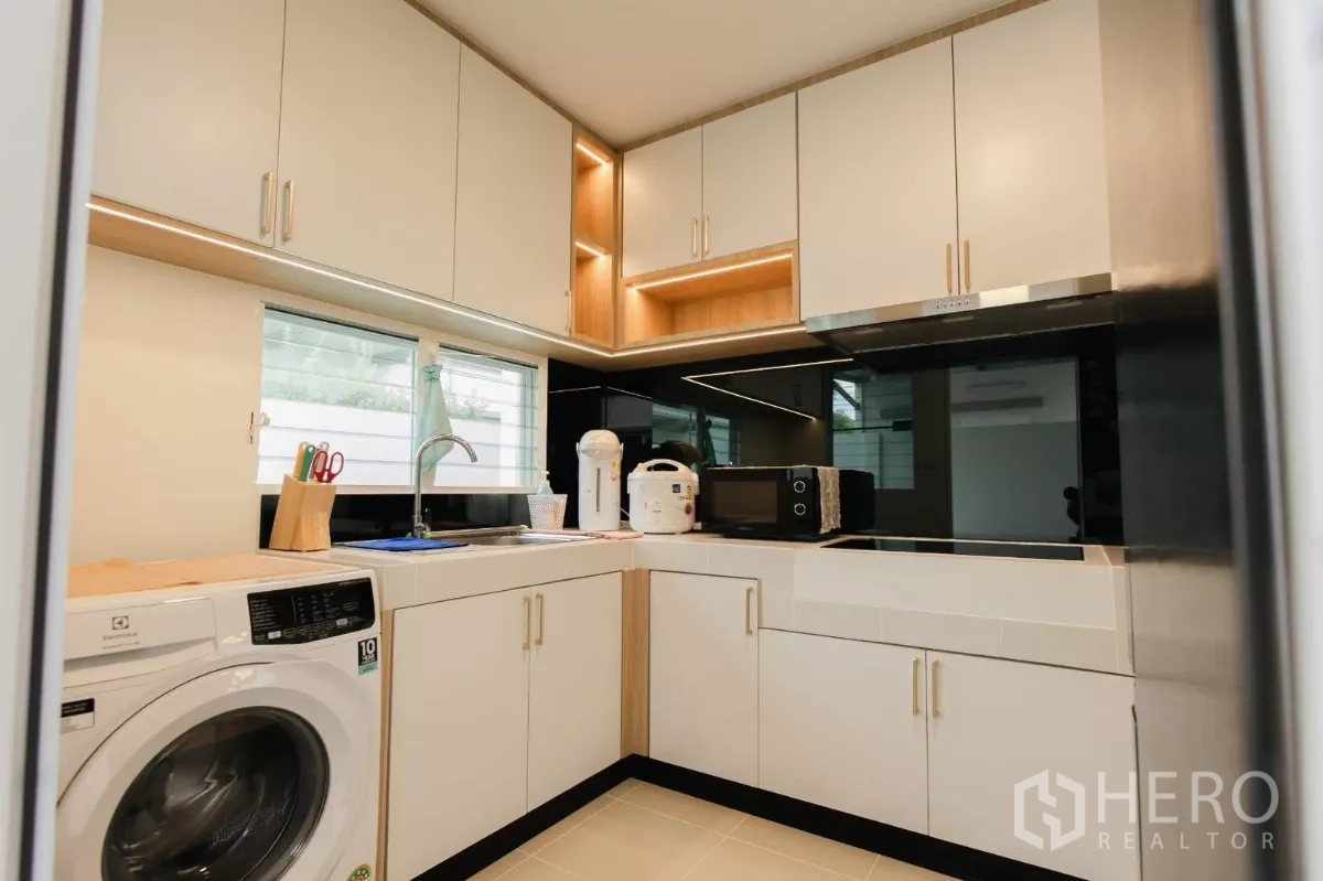 独立式住宅 出租或出售在Bang Phli, Samut Prakan - U型厨房，白色橱柜、吊柜灯与感应炉灶。