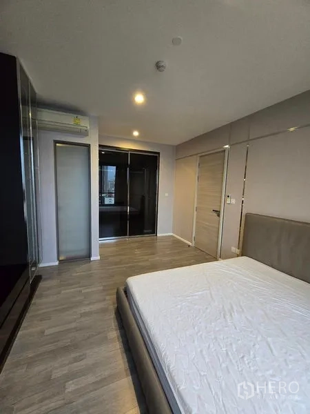 Condominium for rent - Bedroom angle showing wardrobe, wood floors and soft ceiling lights.