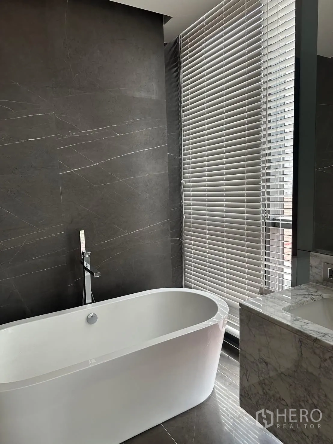 Condominium for rent or sale in Watthana, Bangkok - Bathroom with freestanding bathtub, window blinds, and marble vanity.