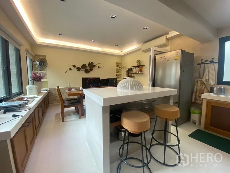 Detached House for sale in Khlong Toei, Bangkok - Modern kitchen with island breakfast bar, stools, and stainless refrigerator.