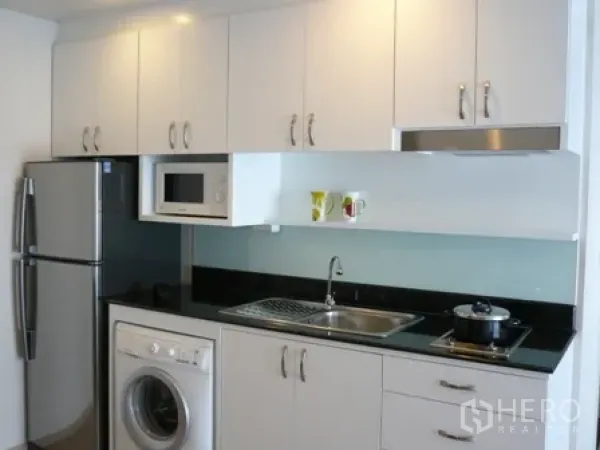 公寓 出租在Watthana, Bangkok - 紧凑厨房，白色橱柜、洗衣机、微波炉与灶台。