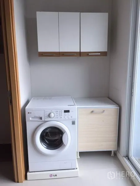 公寓 出租或出售在Ratchathewi, Bangkok - 洗衣区配滚筒洗衣机、收纳柜及通往阳台的推拉玻璃门。