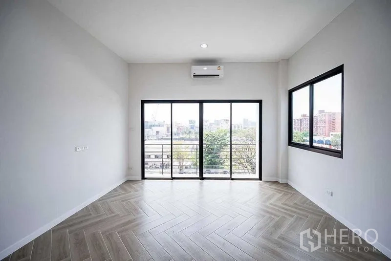 Home Office for rent in Suan Luang, Bangkok - Corner room with herringbone wood flooring, sliding doors to a balcony, and city views.
