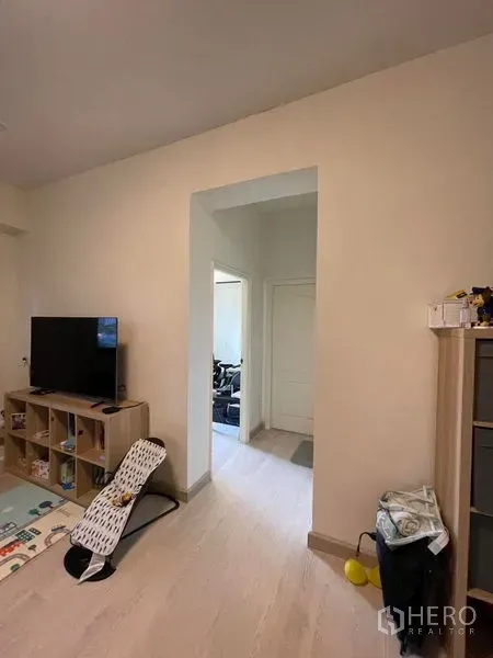 Condominium for sale in Sathon, Bangkok - Living area corridor with TV stand and shelving, leading to bedrooms over light flooring.