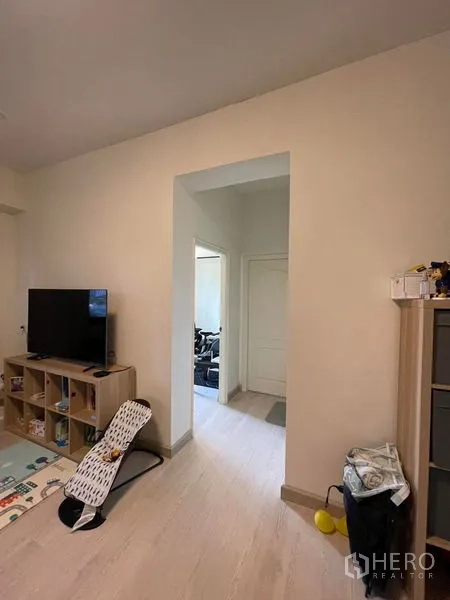 Condominium for sale in Sathon, Bangkok - Living area corridor with TV stand and shelving, leading to bedrooms over light flooring.