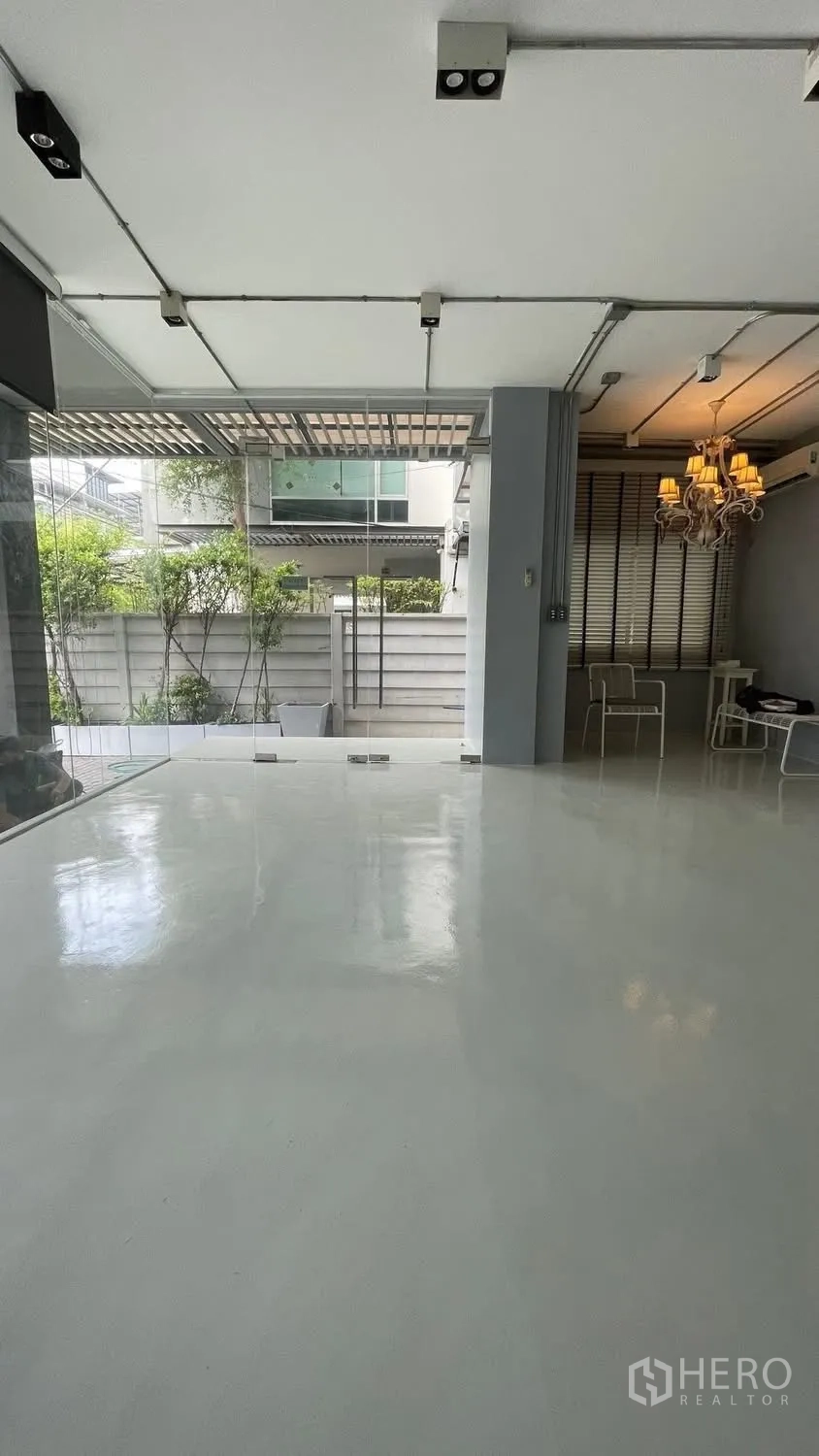 家庭办公室 for rent or sale in Wang Thonglang, Bangkok - 一层开放空间，亮面地坪、玻璃门与小花园景。