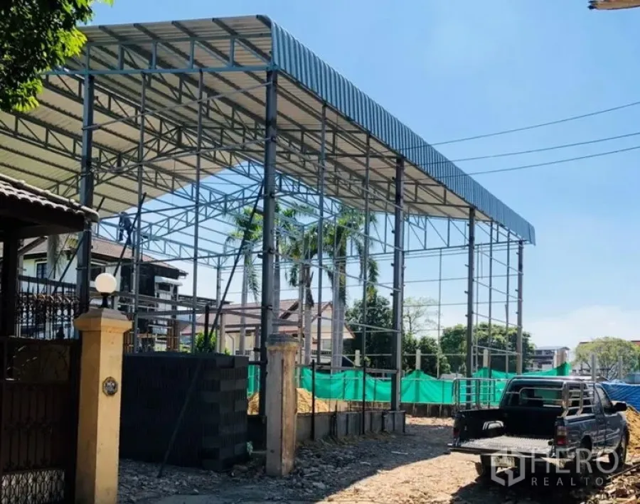 Warehouse for rent in Wang Thonglang, Bangkok - High-clearance steel-frame warehouse under construction with metal roof, pickup truck and building materials on site.
