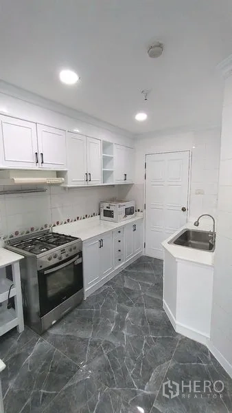 คอนโด ให้เช่าในWatthana, Bangkok - ครัวแบบแกลลีย์ เตาแก๊ส ไมโครเวฟ อ่างล้างจาน และตู้สีขาวพื้นลายหินอ่อน