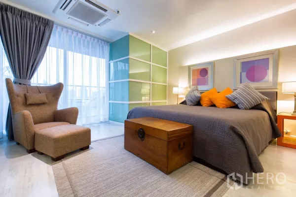 公寓 出租在Pathum Wan, Bangkok - 主卧配特大床、抱枕、贵妃椅与推拉玻璃衣柜，可通往阳台。