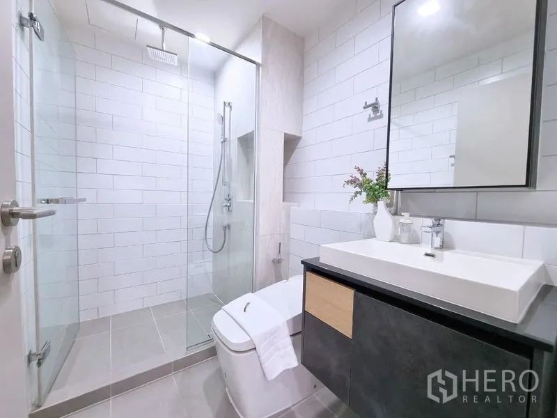 公寓 出售 - 现代浴室，玻璃淋浴房、台上盆与白色地铁砖。