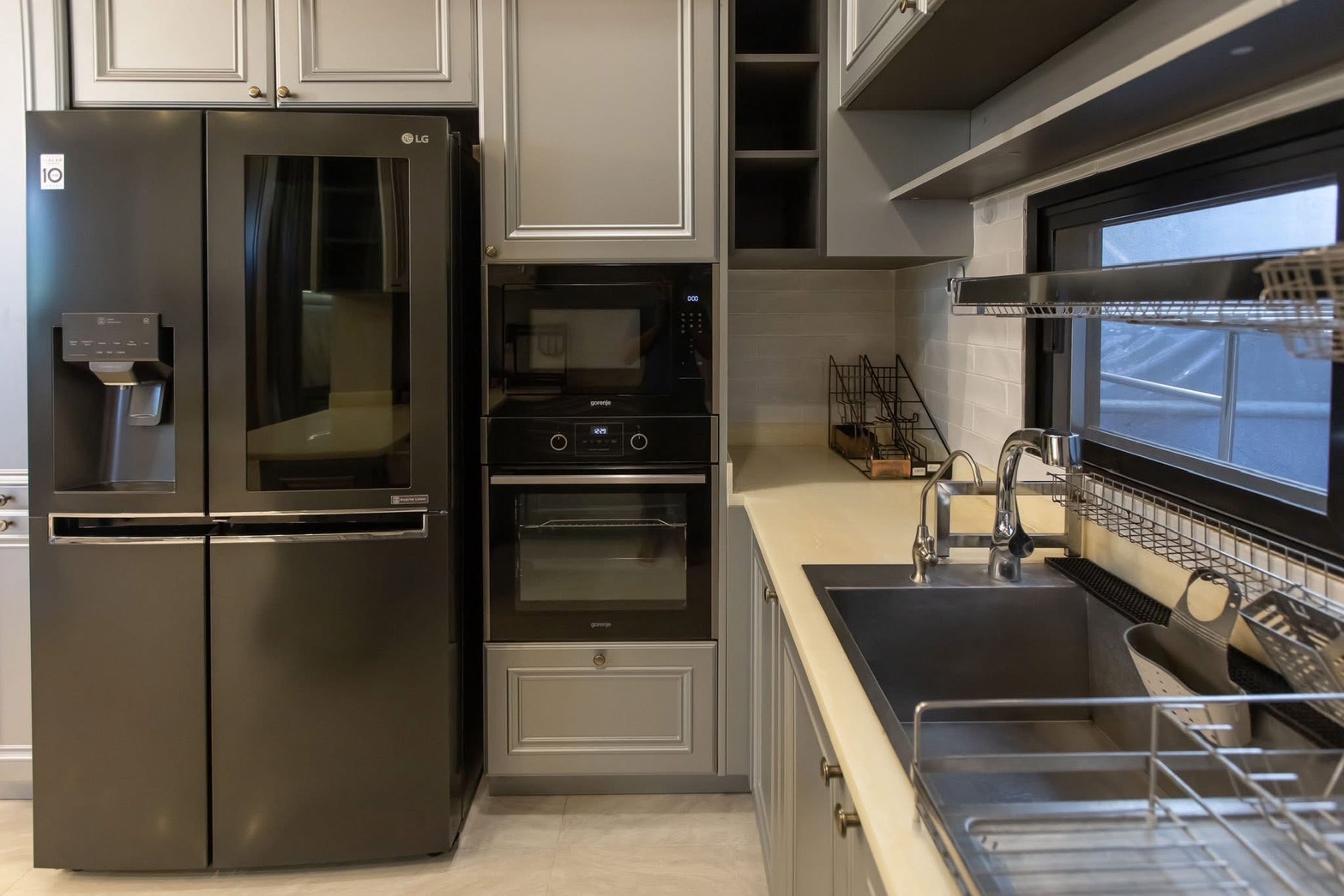 独立式住宅 出租在Lat Phrao, Bangkok - 现代灰色厨房，配黑色LG对开门冰箱、嵌入式烤箱和不锈钢水槽。