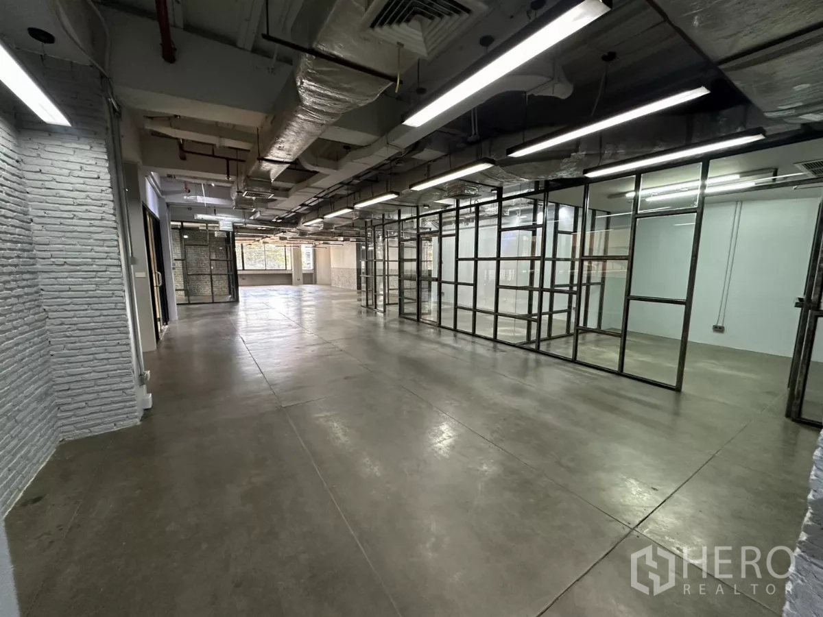 办公空间 出租 - 开放区域，白色砖墙、玻璃房与长条灯。