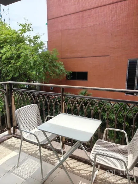 Condominium for rent or sale in Pathum Wan, Bangkok - Private balcony with metal railing featuring a small bistro table and two chairs with leafy outlook.
