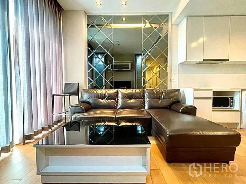 Condominium for rent in Bangkok - Living room close-up showing brown leather sofa and black glass coffee table.