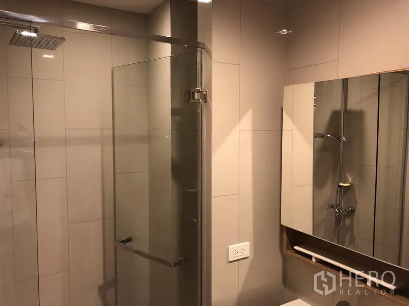 公寓 出租在Watthana, Bangkok - 现代浴室，玻璃隔间雨淋花洒与镜柜。