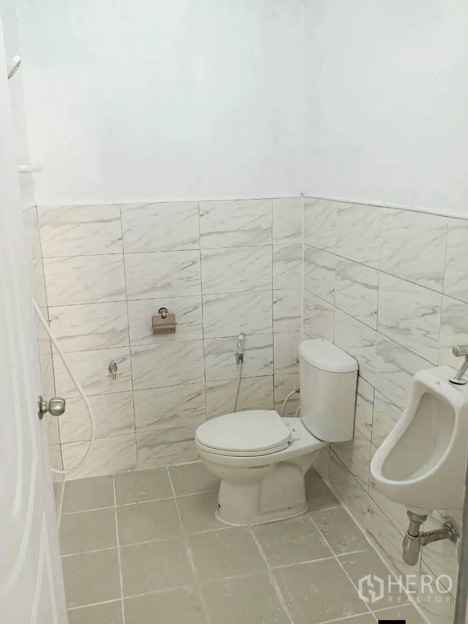 Warehouse for rent in Prawet, Bangkok - Restroom with toilet, urinal, handheld bidet and tiled walls and floor.