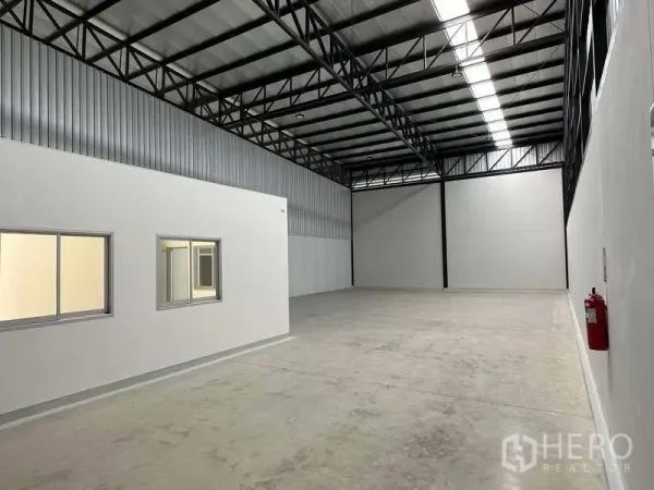 Factory for rent in Bang Phli, Samut Prakan - Spacious factory floor with high steel truss roof, skylight strip and attached office box.