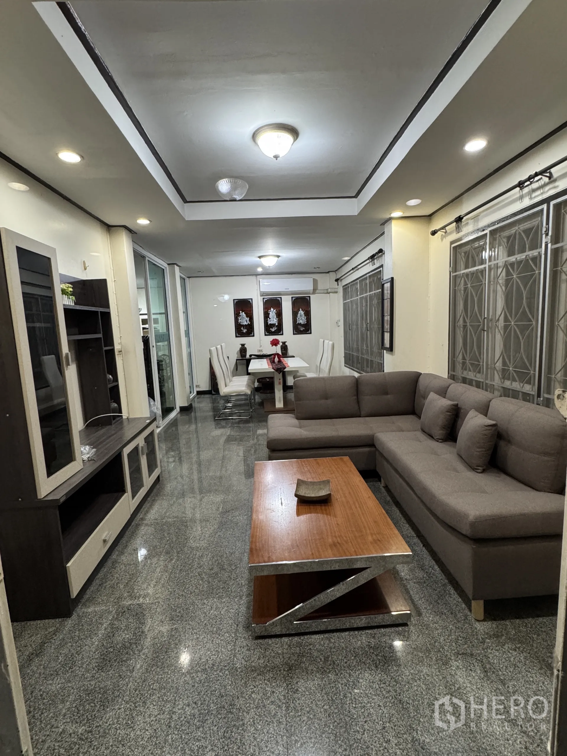 บ้าน ให้เช่าในMin Buri, Bangkok - พื้นที่นั่งเล่นและรับประทานอาหารแบบโอเพ่นแปลน โซฟาเข้ามุม ตู้ทีวี พื้นแกรนิต และไฟดาวน์ไลท์