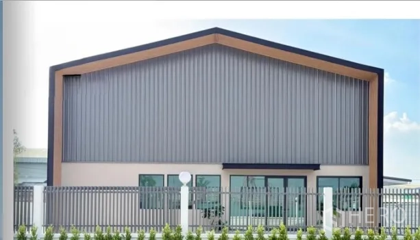 Warehouse for sale in Bang Bua Thong, Nonthaburi - Front facade of a modern gable-roof warehouse with glass entry behind a metal fence.
