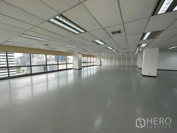 Office Space for rent - Spacious corner office with grid ceiling, fluorescent lighting and windows on two sides.