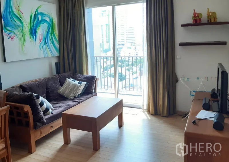 คอนโด ให้เช่าในKhlong Toei, Bangkok - ห้องนั่งเล่นสว่าง โซฟาไม้ โต๊ะกลาง และประตูกระจกสไลด์ออกสู่ระเบียงวิวเมือง