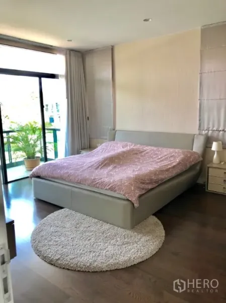 Detached House for rent in Bang Kapi, Bangkok - Master bedroom with king bed, hardwood floors, balcony access and a round rug.