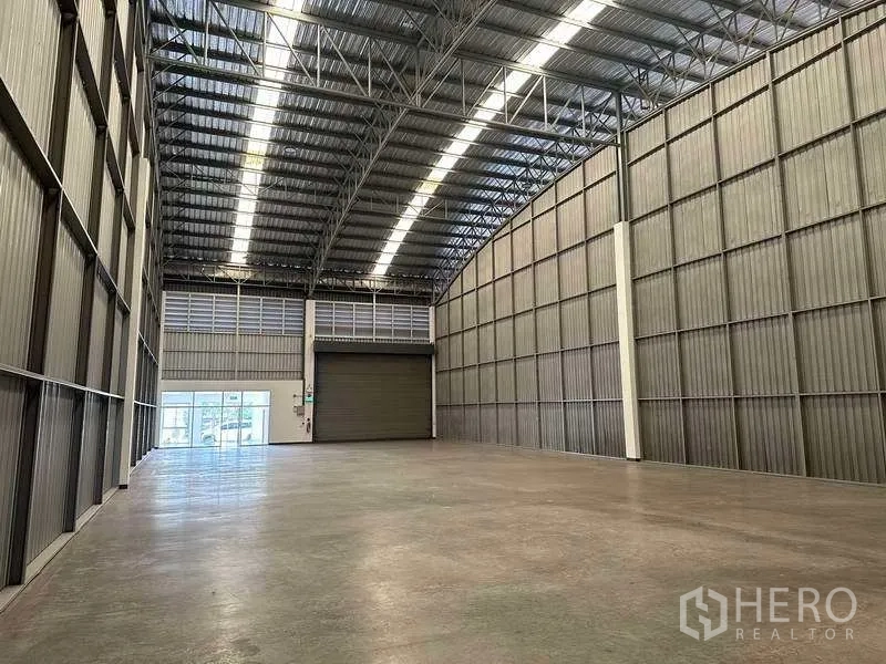 Factory for rent in Bang Sao Thong, Samut Prakan - High-ceiling storage space with smooth concrete floor and metal wall panels.
