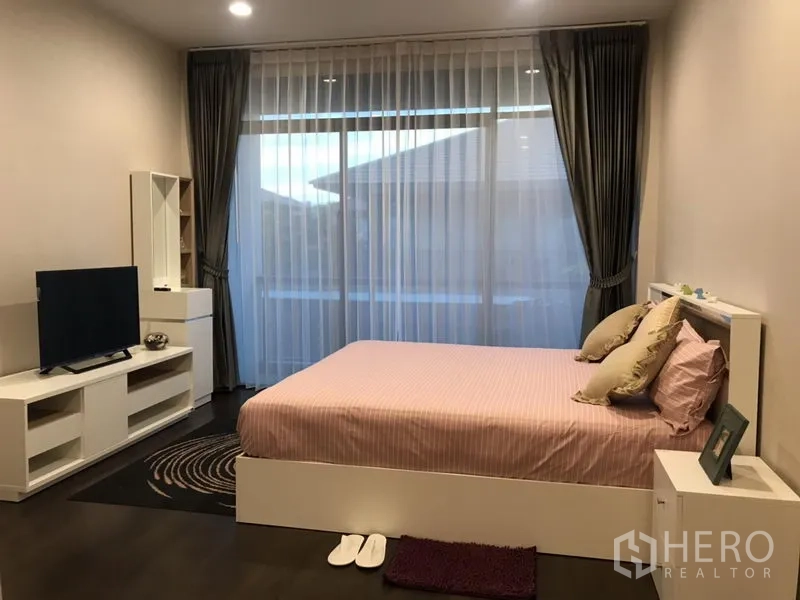 Detached House for rent in Bang Kapi, Bangkok - Spacious master bedroom with large windows, sheer curtains, TV unit and balcony access.