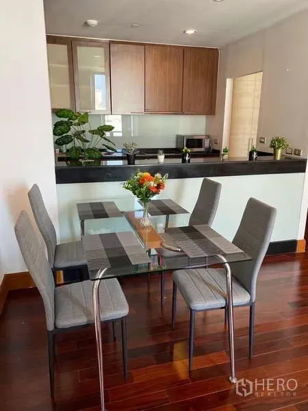 คอนโด ขายในSathon, Bangkok - โต๊ะกินข้าวกระจกสำหรับ 4 ที่นั่ง ข้างครัวเปิดตู้ไม้และท็อปสีเข้ม ในคอนโด Ascott Sathorn.