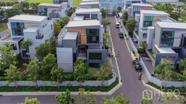 Detached House for rent in Saphan Sung, Bangkok - Aerial view of a modern gated street lined with contemporary multi‑level detached houses and lush landscaping.