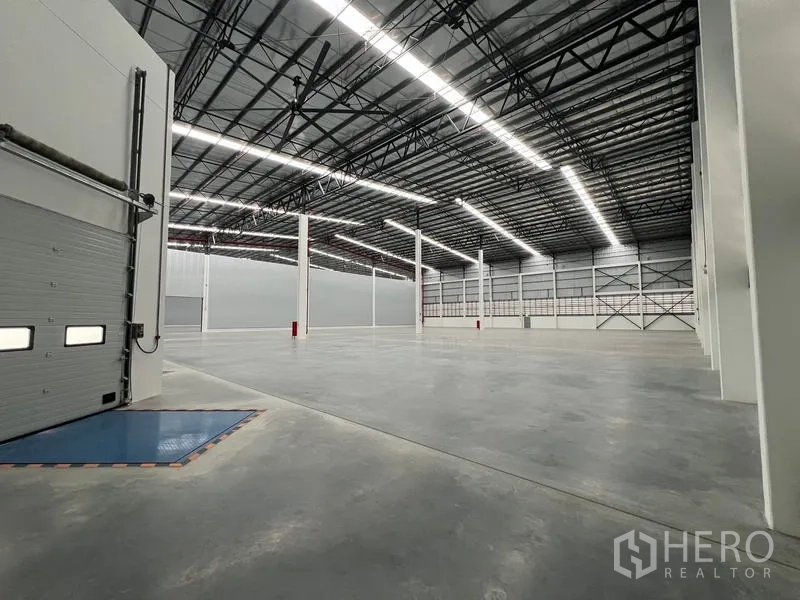 Warehouse for rent in Chon Buri - Open warehouse floor viewed from loading zone with columns and visible fire piping.