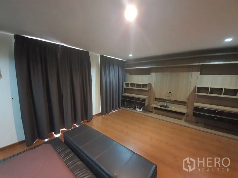 Townhouse for rent in Phaya Thai, Bangkok - Large bedroom with dark curtains and custom wall-to-wall shelving and workstations.