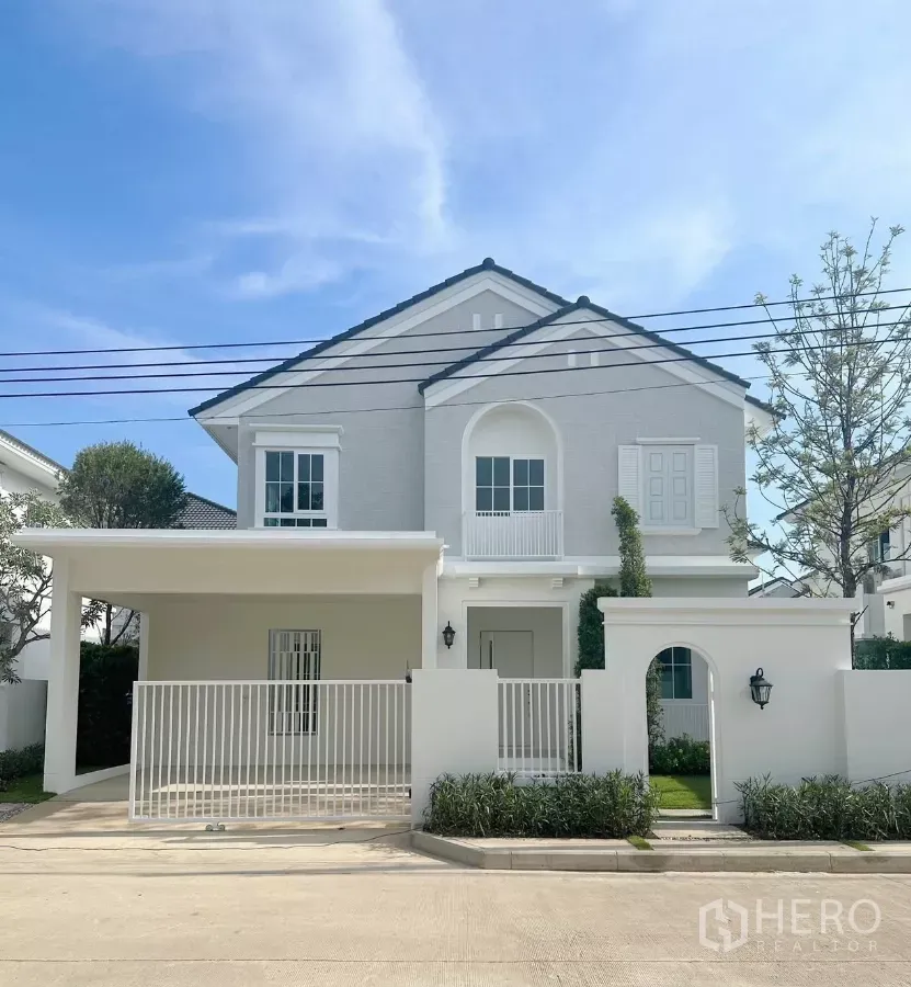 Detached House for rent in Bang Phli, Samut Prakan - Front exterior of a two-storey white detached house with gated carport and small garden.