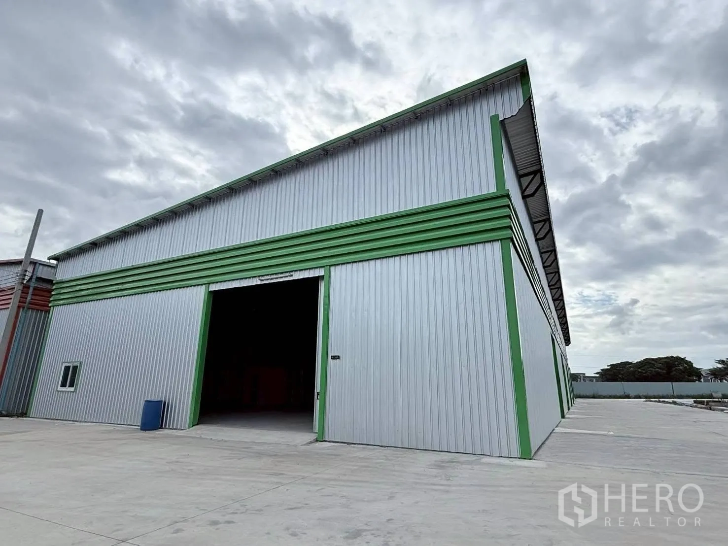 Warehouse for rent in Bang Phli, Samut Prakan - Warehouse exterior with large sliding entry door and paved yard for loading and parking.
