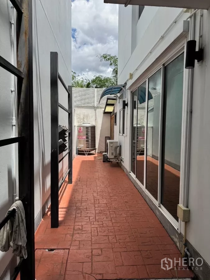 Detached House for sale - Side terrace with red stamped-concrete flooring, sliding glass doors, and outdoor AC units.