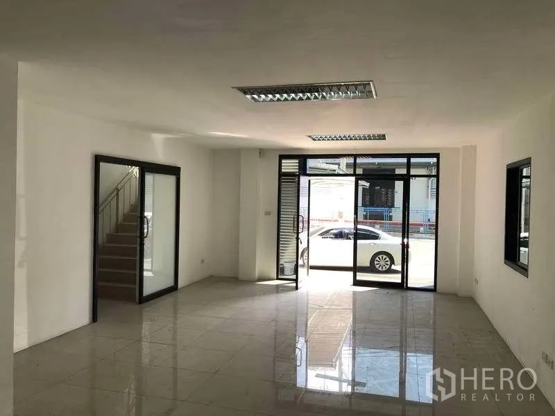 Factory for rent or sale in Bang Phli, Samut Prakan - Bright ground-floor office with tiled floors, glass frontage and a staircase to the upper level.
