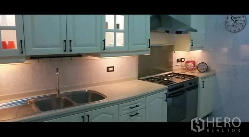 公寓 出租在Khlong Toei, Bangkok - 现代西式厨房，白色橱柜、双水槽、燃气灶与抽油烟机，灯光充足。